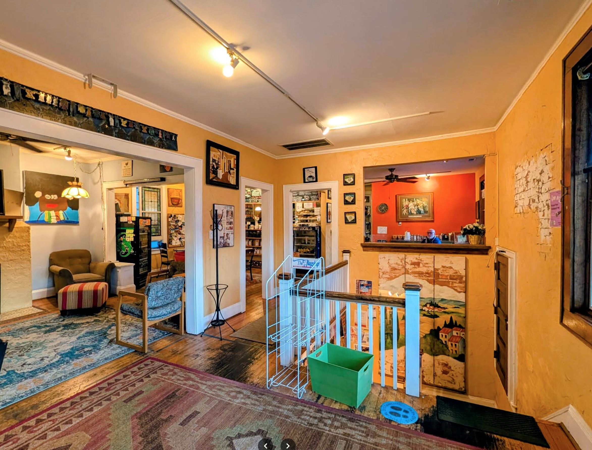 Eclectic interior of Fair Grounds Coffee Cafe showing art-covered walls and historic staircase