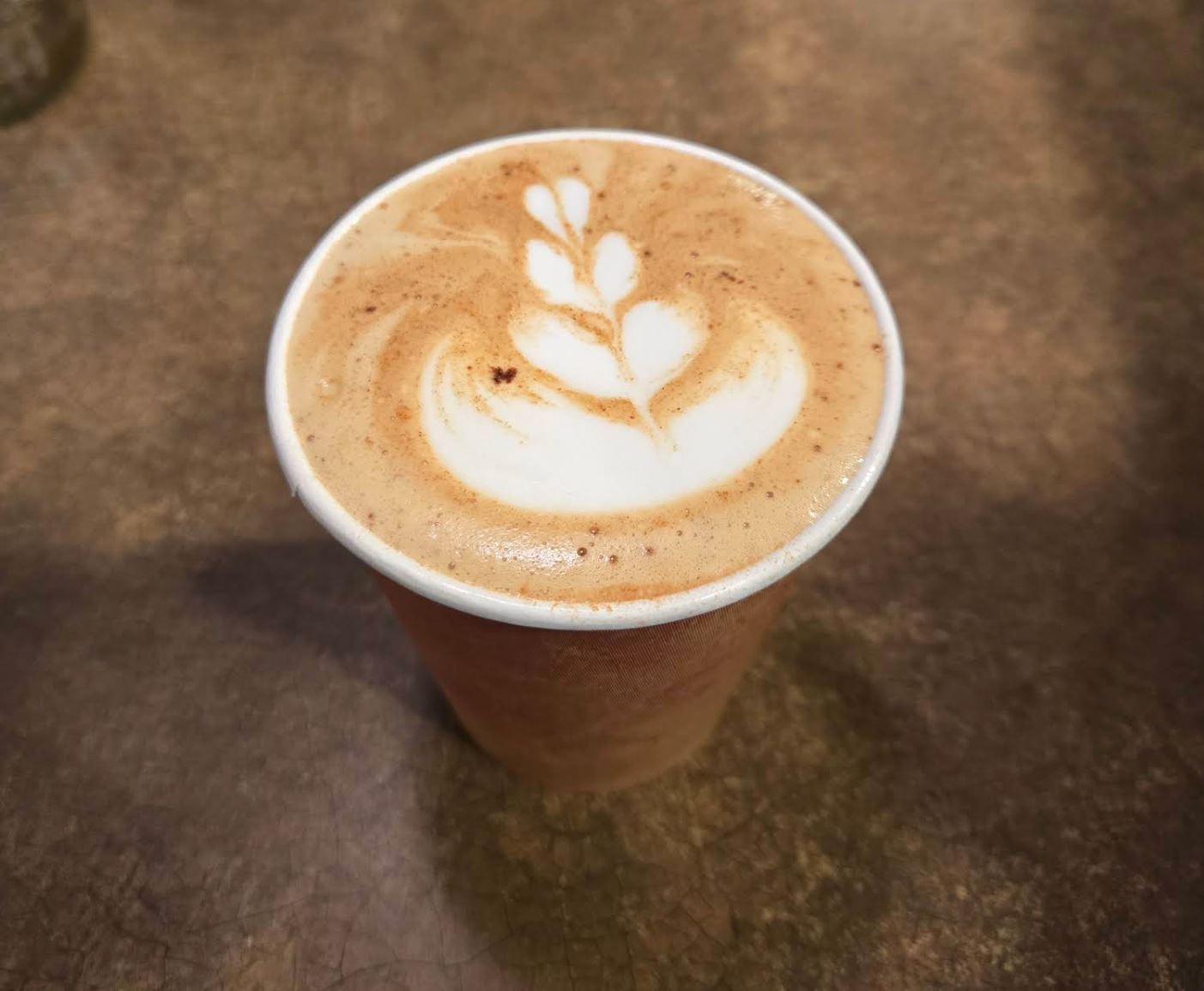 Latte with leaf latte art in a ceramic cup at Fair Grounds Coffee Cafe