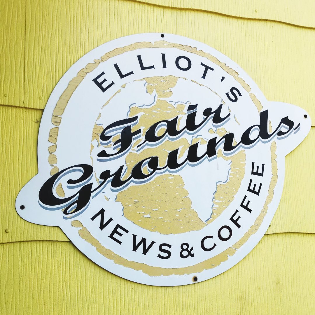 Elliot's Fair Grounds News and Coffee sign mounted on yellow building exterior