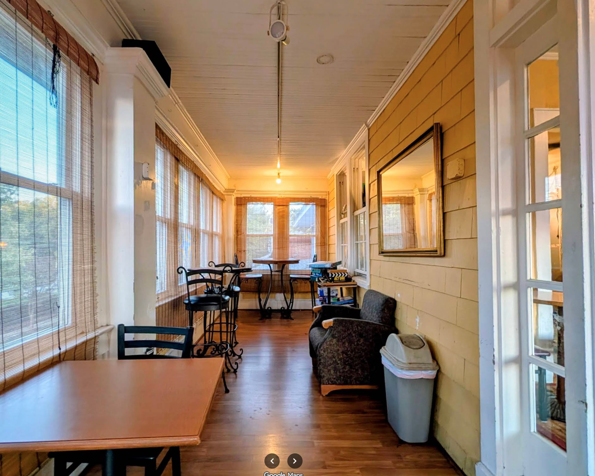 Sun-porch seating corridor with warm pendant lights and hardwood floors at Fair Grounds